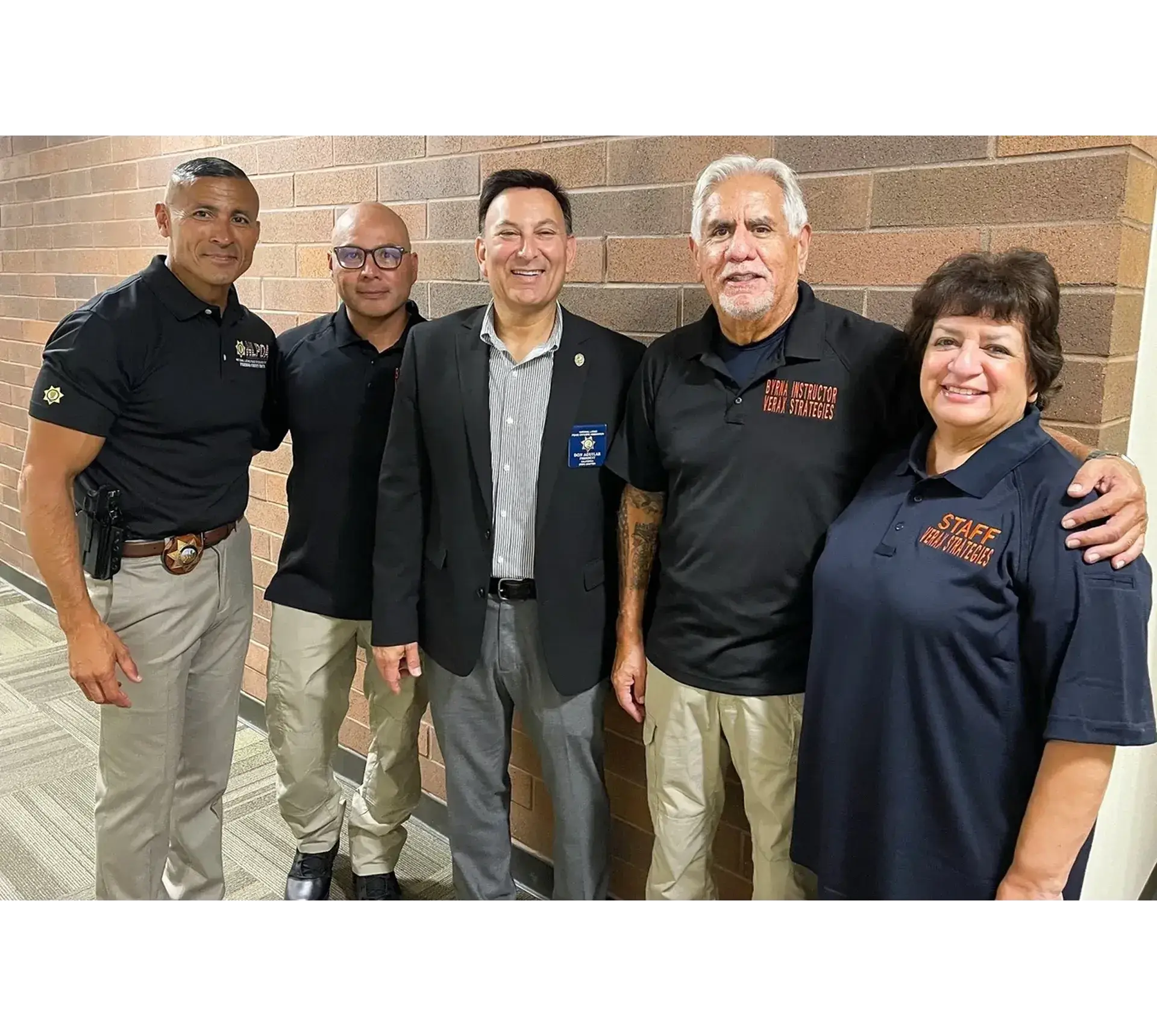 Group of five people smiling, standing indoors.