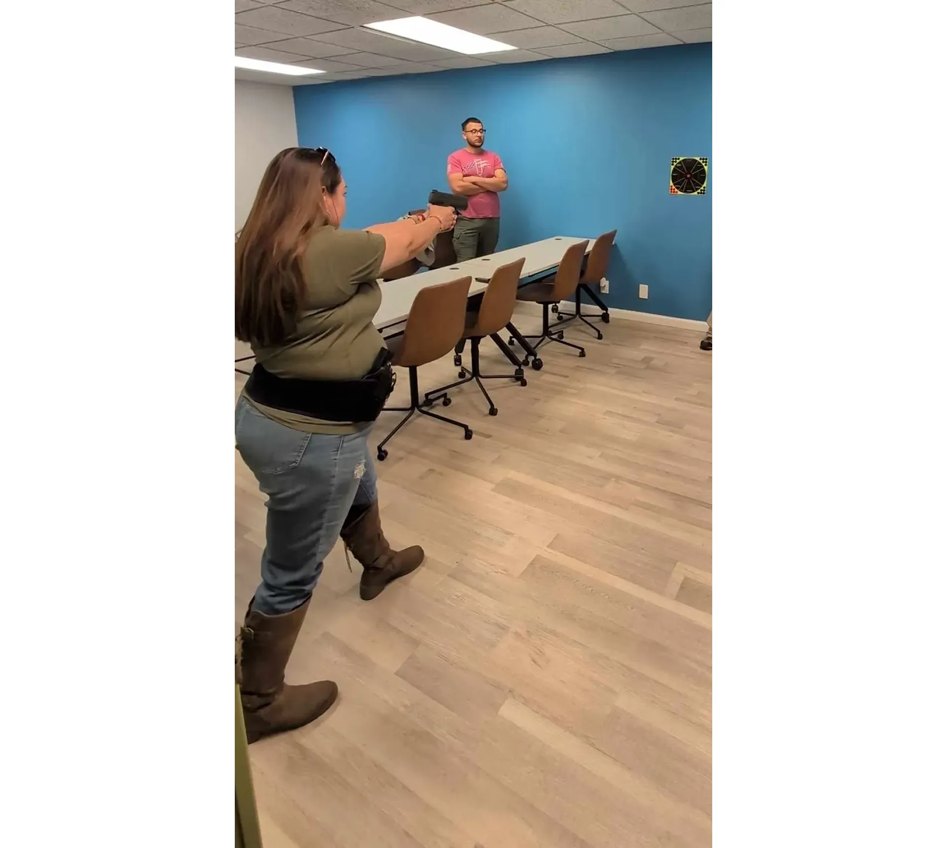 Woman aiming at target in office room.