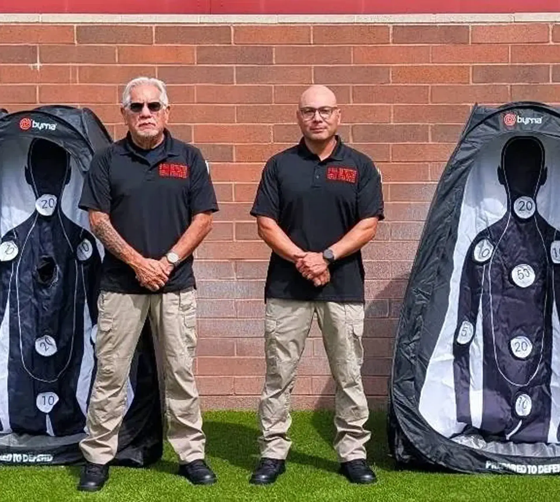 Two men standing between shooting targets.