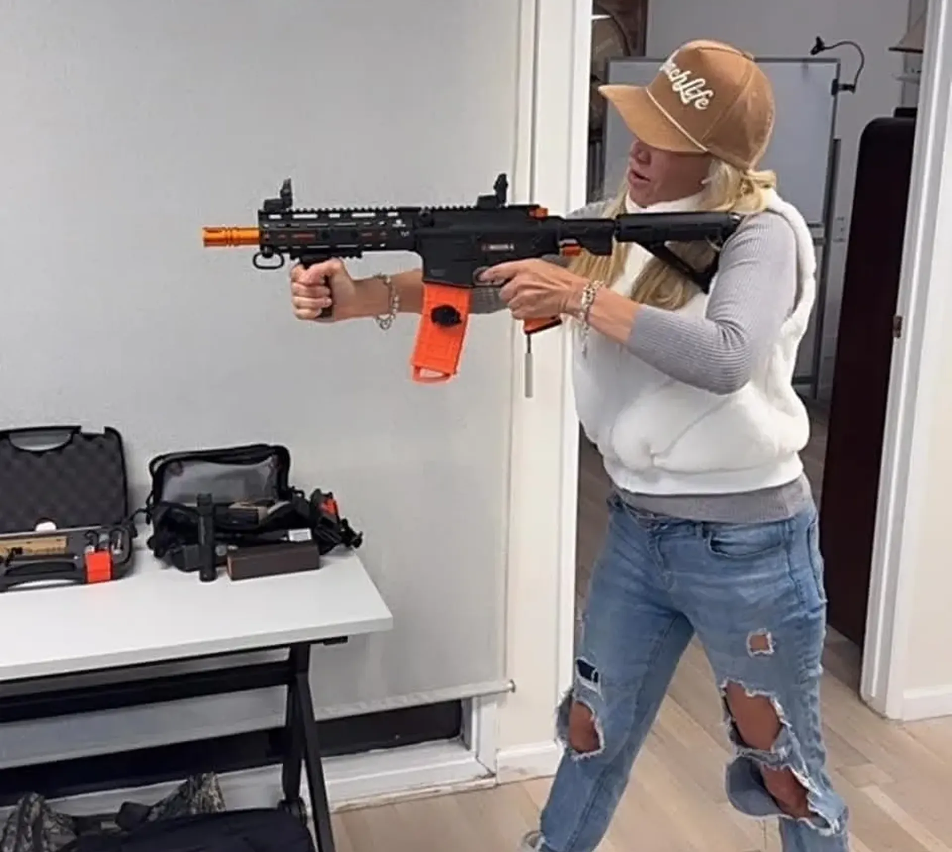 Person aiming toy gun indoors near table.