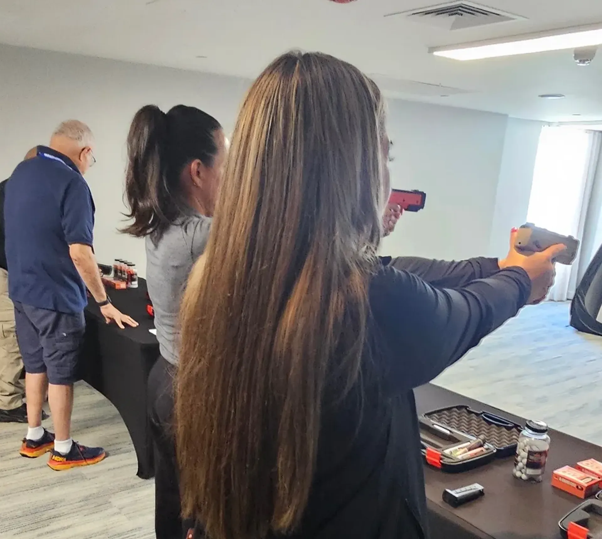 People aiming devices at indoor shooting range.