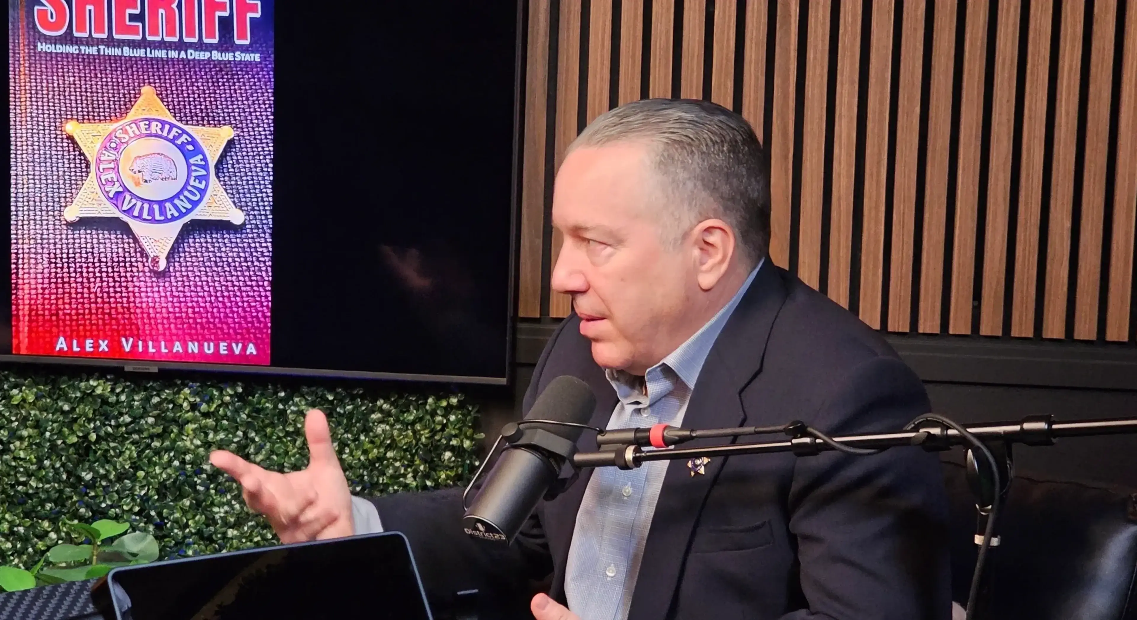Man speaking into microphone, book cover visible.