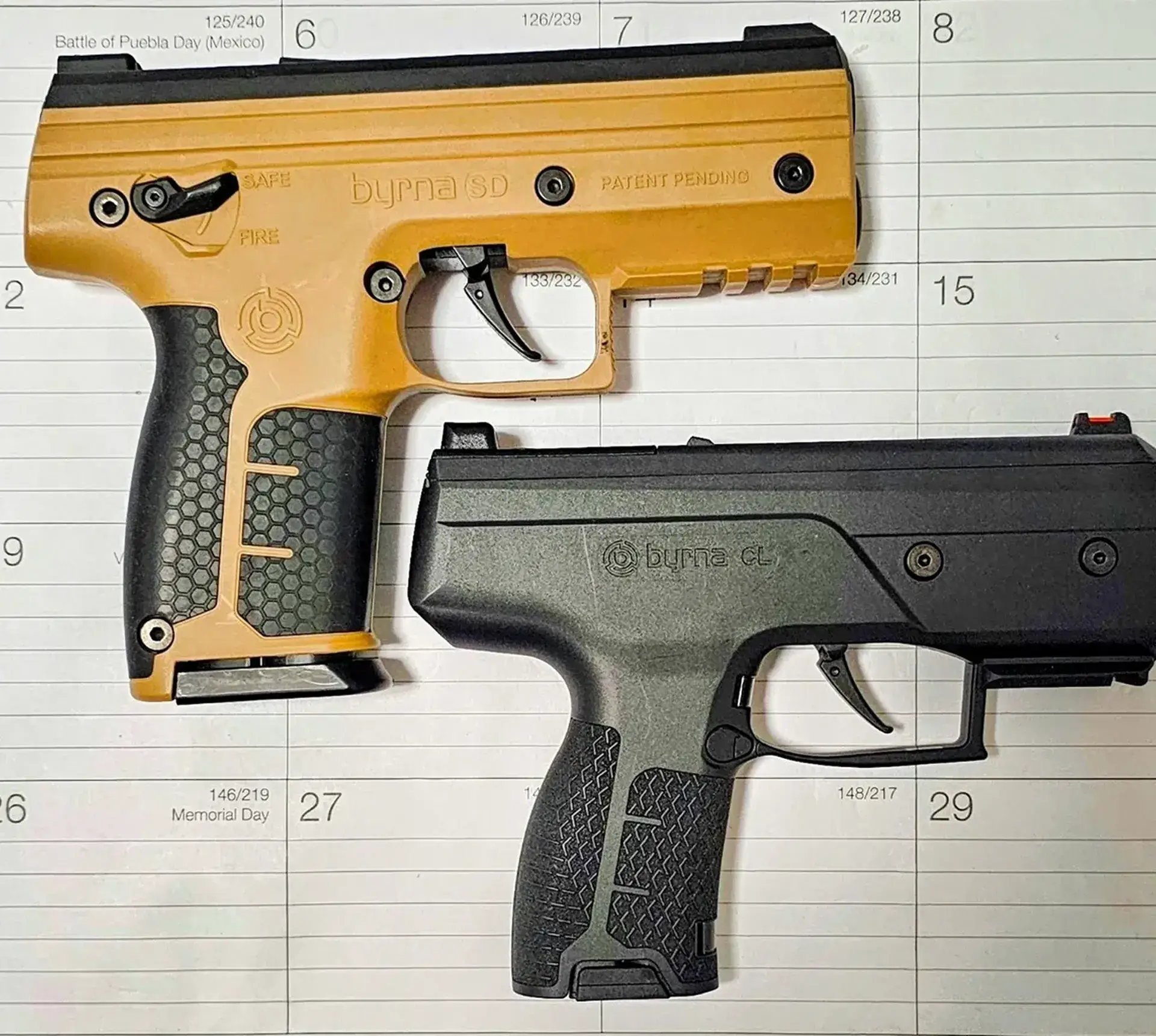 Two non-lethal pistols on calendar background.