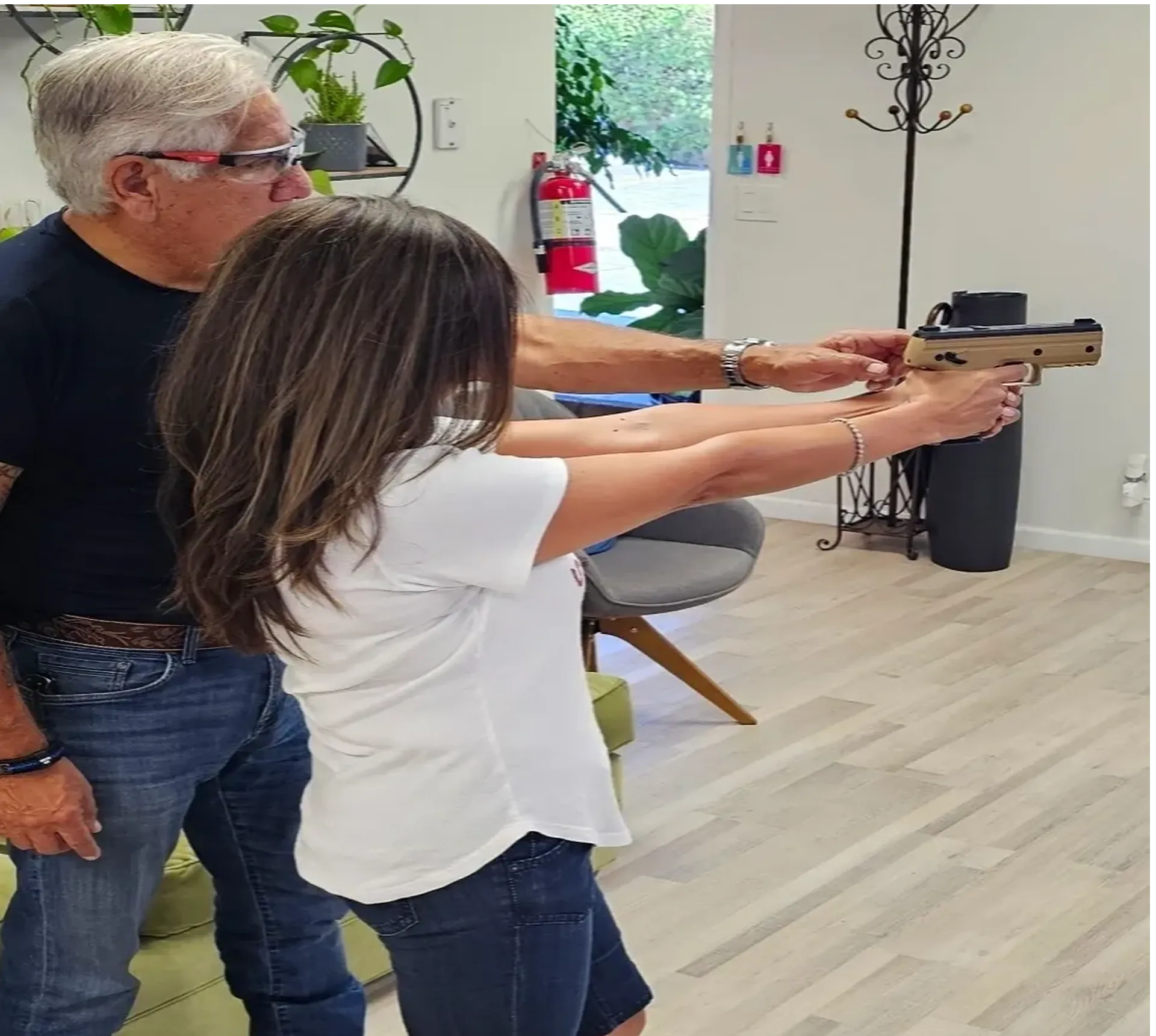 Man instructing woman on handgun use indoors.