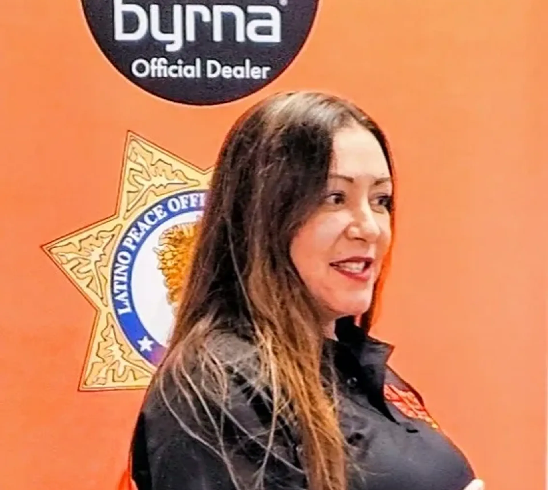 Woman standing by Byrna official dealer sign.