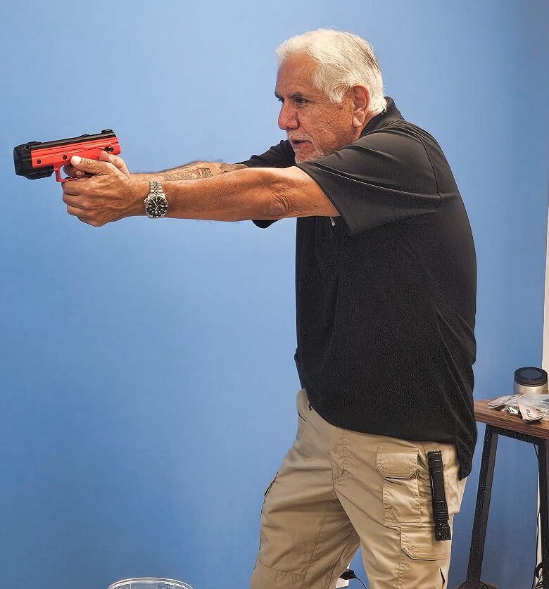 Man holding a training pistol, aiming forward.